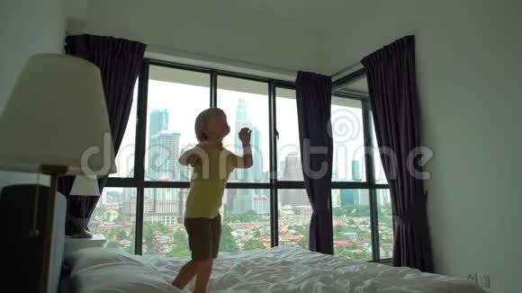 一个小男孩在床上跳跃的慢镜头床垫和枕头概念视频的预览图