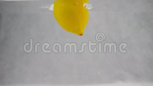 一个柠檬掉进水里气泡在缓慢地运动在白色背景下分离的水果视频的预览图