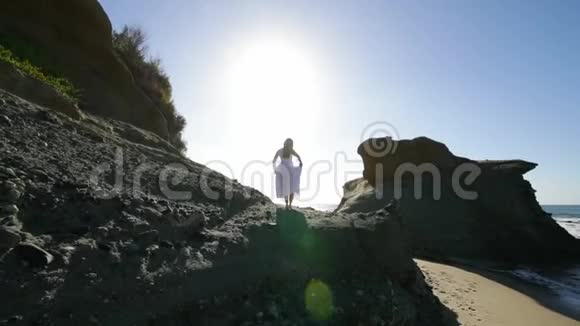 自由概念穿着白色连衣裙的女人站在岩石上跳舞像鸟一样飞翔移动视频的预览图
