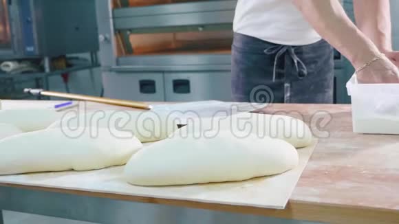 专业面包师在烘焙前将面粉倒在生面包上视频的预览图