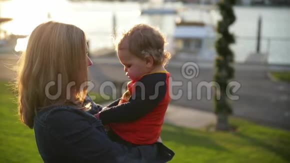 可爱时尚的年轻母亲和她的儿子享受美好的晴天儿子坐在母亲的手上视频的预览图