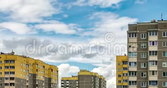 黄色多层公寓楼背景下白色蓬松滚动云的时间流逝片段视频的预览图