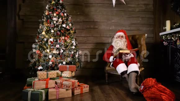 圣诞老人在圣诞树附近读一本书视频的预览图