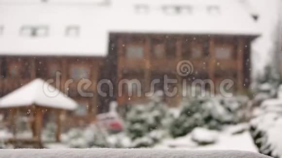 冬天背景模糊大雪期间山村的木制小屋与针叶常绿景观视频的预览图