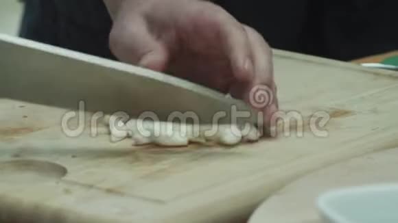 切法的特写用菜刀在木切割板上细切大蒜视频的预览图