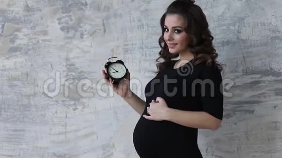 的孕妇手里拿着一个钟未来母亲的美丽肖像等待孩子的女人宝贝视频的预览图
