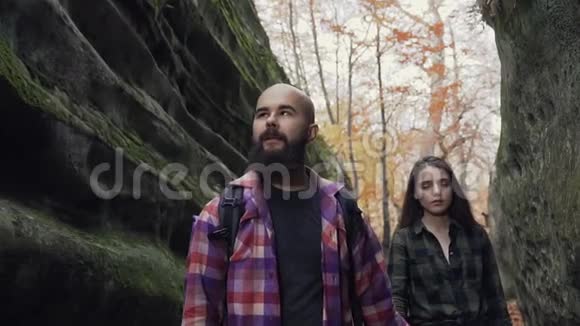 快关门一个留着长发的女人和一个留着胡子的男人走在石头中间的一条人行小径上视频的预览图