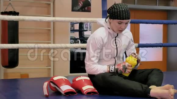 女踢脚手坐在拳击台上训练后喝水视频的预览图