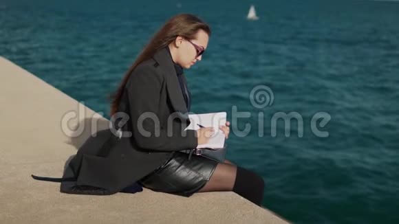 女人在海边的户外素描书上画素描慢镜头视频的预览图