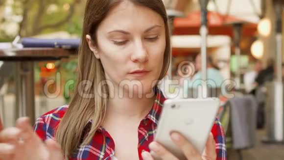 坐在咖啡馆里看菜单的漂亮女人女人用手机浏览喝酒视频的预览图