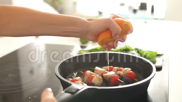 年轻的家庭主妇在厨房做饭把橘子捏在煎锅上慢动作视频的预览图