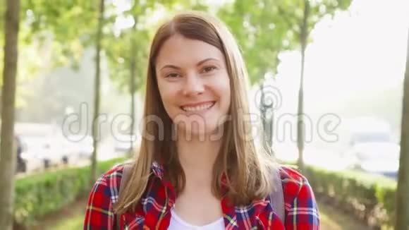 幸福快乐的年轻女人享受大自然的肖像漫步在绿色公园微笑着面对镜头视频的预览图