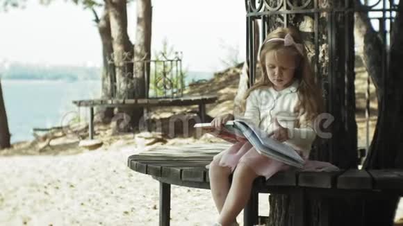 一个可爱的女孩坐在树林里看书视频的预览图
