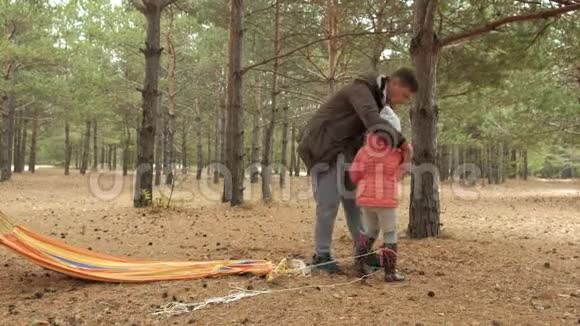 一个在树林里放吊床的年轻人女儿在附近散步视频的预览图