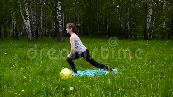 年轻漂亮的青少年女孩在户外练习健身运动在夏天的公园里高清拍摄静态摄像机视频的预览图