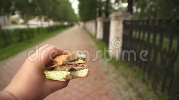 一个男人正在街上吃快餐手里拿着一个汉堡包视频的预览图