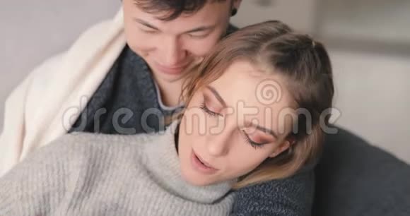 爱情年轻夫妇在家里的沙发上拥抱在一起视频的预览图
