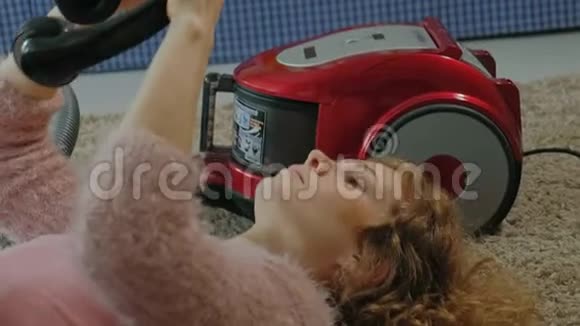 快乐的年轻女性或家庭主妇用吸尘器躺在半头手机上用手机听音乐视频的预览图