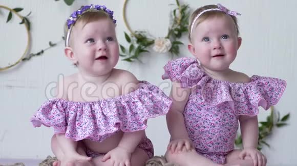 穿着粉色衣服的双胞胎摆在墙上的照片上装饰视频的预览图