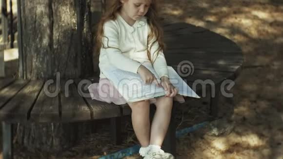 一个可爱的女孩坐在树林里看书视频的预览图