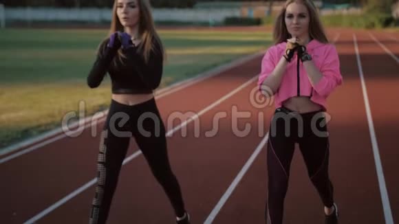 两个漂亮的体育女孩在体育场的火车上身材很好女孩在日落时训练视频的预览图