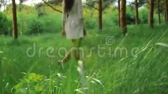 穿着白色裙子的瘦小女孩走在绿色的树林里视频的预览图