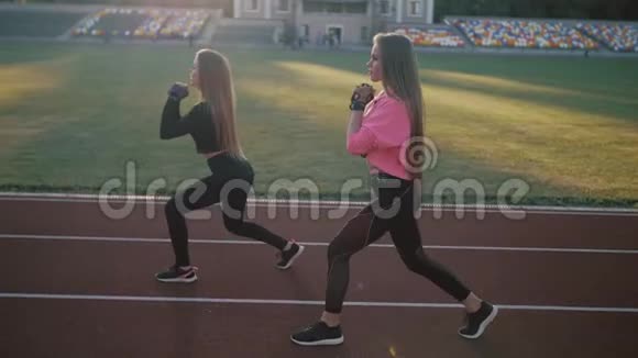 两个漂亮的体育女孩在体育场的火车上身材很好女孩在日落时训练视频的预览图