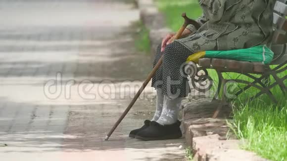 一位祖母一位无家可归的带拐杖的贫困残疾人坐在公园里的长凳上俄罗斯的贫困观念生活方式视频的预览图