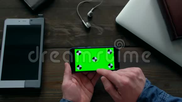 男性使用智能手机木桌上有绿色屏幕视频的预览图
