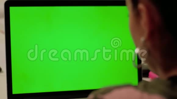 穿迷彩服的女孩用绿色屏幕在笔记本电脑上打视频电话视频的预览图