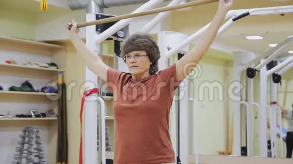 老年妇女提棍在健身室做理疗练习健康体操活跃的老年人视频的预览图