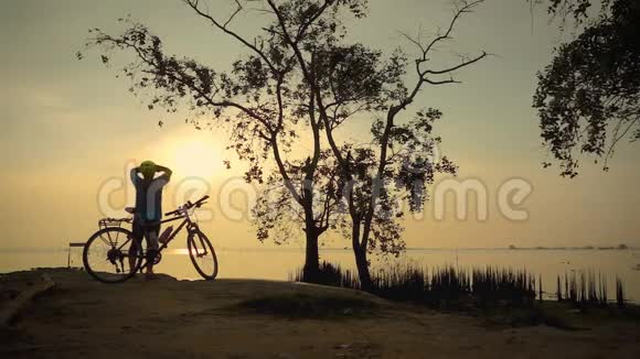 骑自行车的女人在海边骑自行车走路的剪影伸展运动视频的预览图