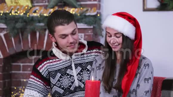 一对年轻的白种人夫妇微笑着看着一支火红的蜡烛视频的预览图