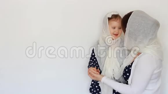 一位戴着头巾的年轻穆斯林妇女抱着一个婴儿母亲和女儿一起玩拥抱和亲吻她光线视频的预览图