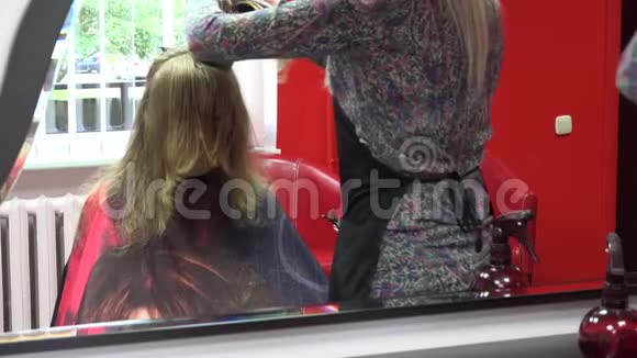 理发师在镜子前梳理和修剪女性顾客的头发4K视频的预览图