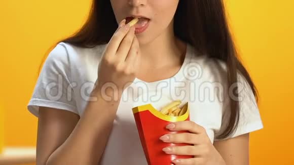 在快餐店吃高脂肪炸薯条的年轻女人不健康的饭菜视频的预览图