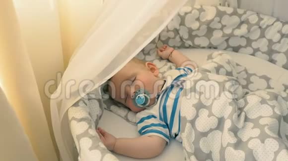 可爱的婴儿在婴儿床上睡觉嘴里有假人视频的预览图