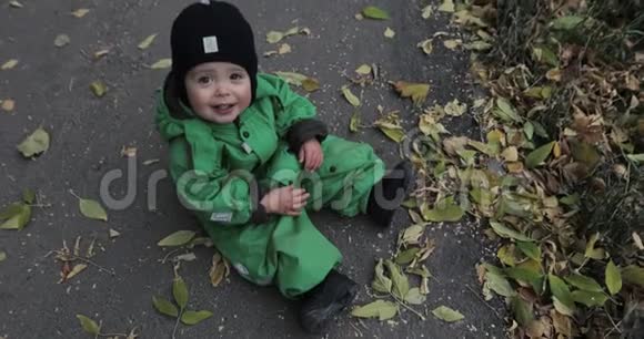 秋天的树叶可爱的小男孩坐在地上视频的预览图