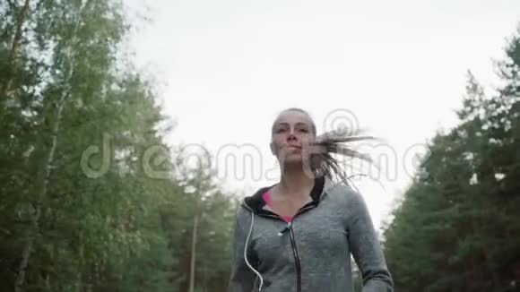 美丽的年轻女孩在公园里跑步那个金发女郎从事田径运动视频的预览图