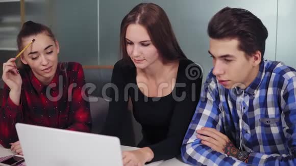 创意商业团队由三个人组成在一个现代化的办公室里在笔记本电脑上工作他们在讨论商业想法视频的预览图