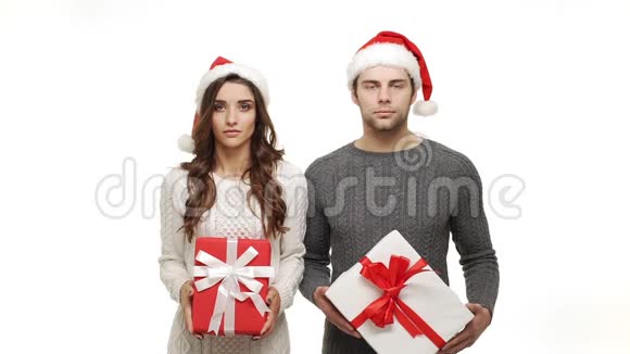 慢动作年轻夫妇穿着毛衣和圣诞帽庆祝圣诞节令人惊讶视频的预览图