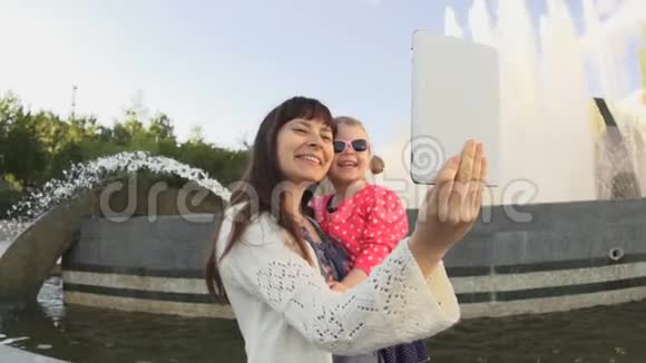 母亲的女儿在日落时分的喷泉上自拍视频的预览图