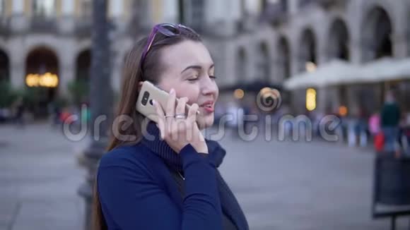 年轻的女商人穿过广场打电话视频的预览图