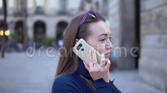 年轻的女商人穿过广场打电话视频的预览图