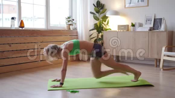 年轻女子在家锻炼高加索女人在瑜伽垫上做体重运动视频的预览图