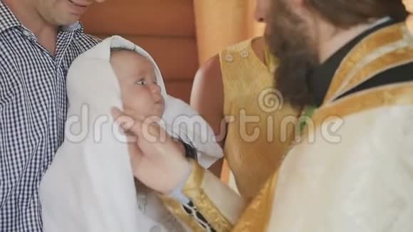 牧师在圣水中接受洗礼后在小婴儿身上套上一条毛巾视频的预览图
