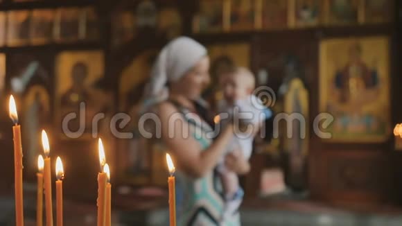在教堂里点燃蜡烛母亲在模糊的背景上带着孩子视频的预览图