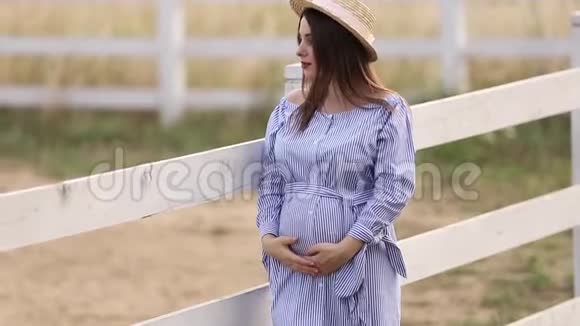 戴帽子的孕妇站在门廊附近农场现场背景视频的预览图