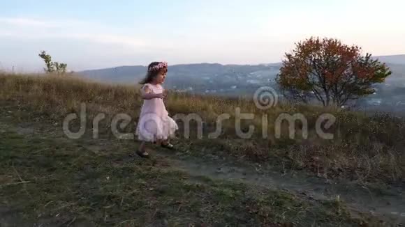 快乐可爱的女孩从山上跑出来背景上令人惊叹的风景视频的预览图