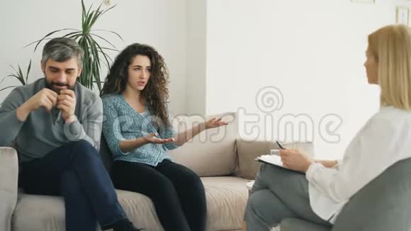 愤怒的女人和婚姻顾问争论和谈论她的丈夫年轻夫妇访问专业心理学家视频的预览图